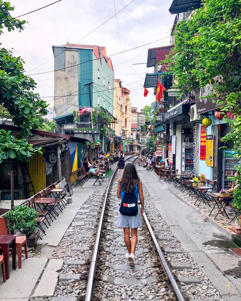 a girl walks on the train tracks between houses