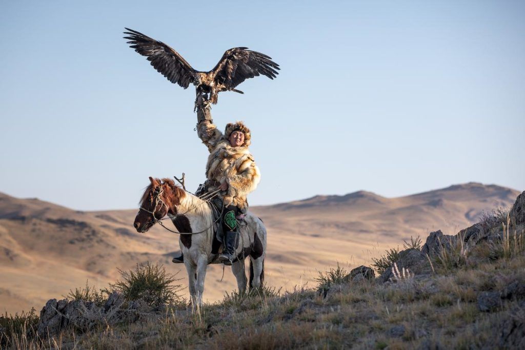 A man on horseback with a bird on his arm in Mongolia