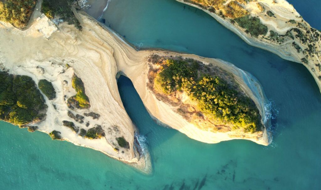 aerial view of white rock formations with green vegetation and turquoise sea