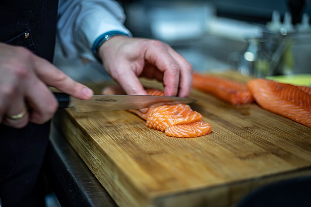 Hand cutting salmon sashimi.