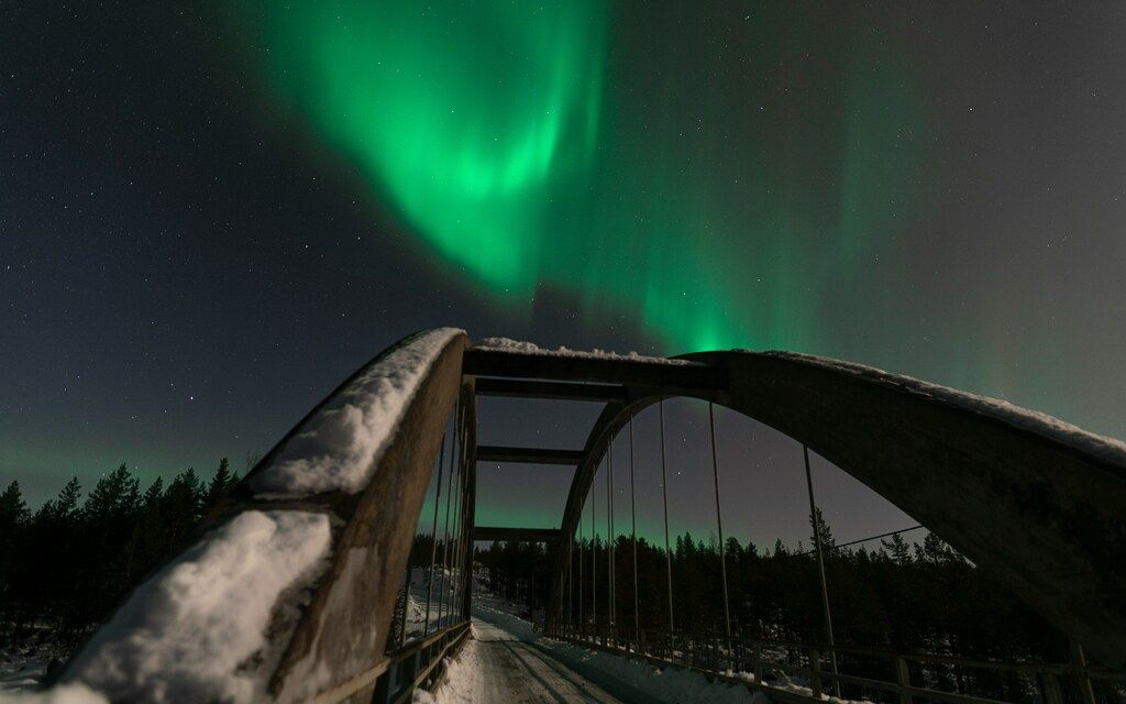 A bridge with green northern lights in the Lapland sky
