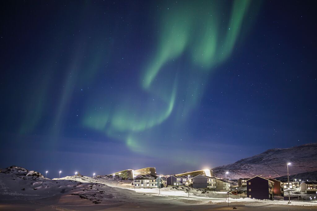 Brown and white houses under the green sky at night in greenland