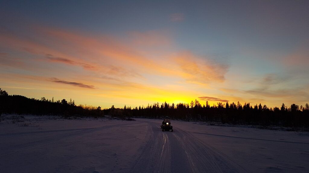 a snowmobile in the snow in Lapland at sunset