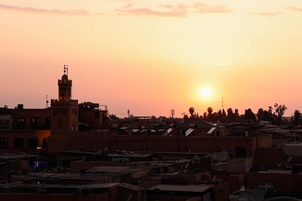 The sun is setting over a city with roofs.