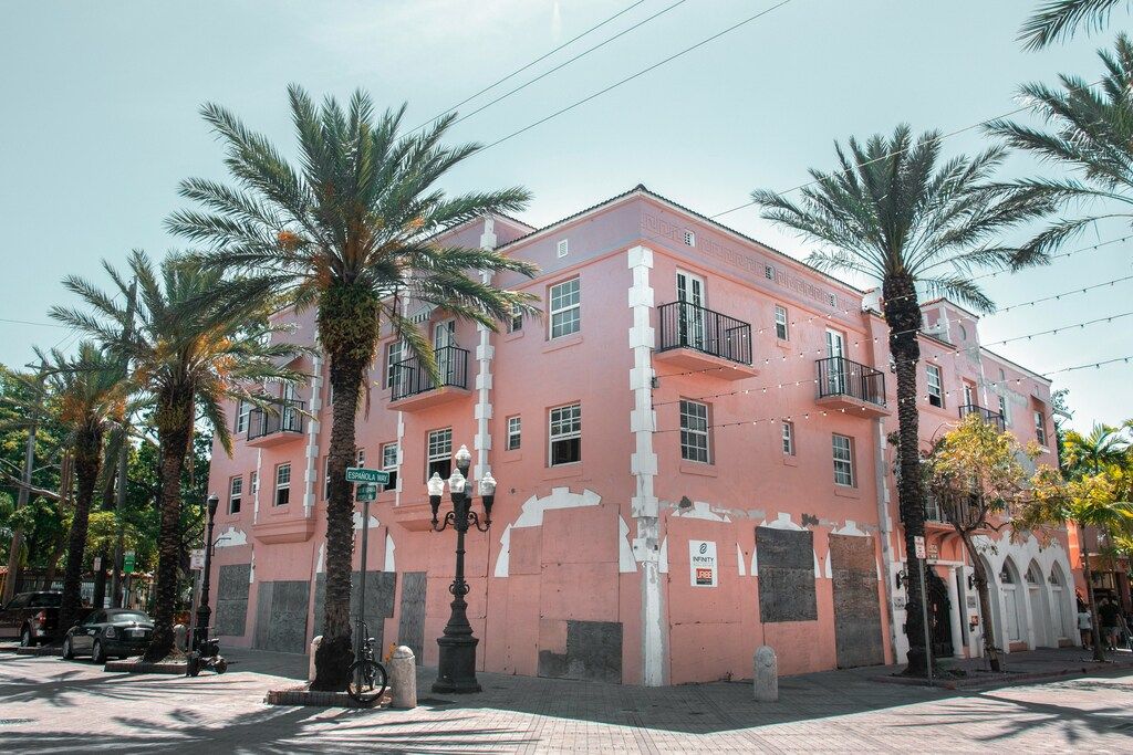 Pink concrete building with palm trees in front.