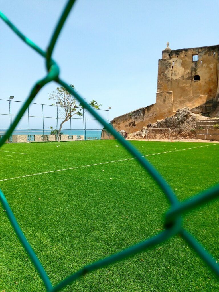 A football pitch behind a fence with an ocean view.
