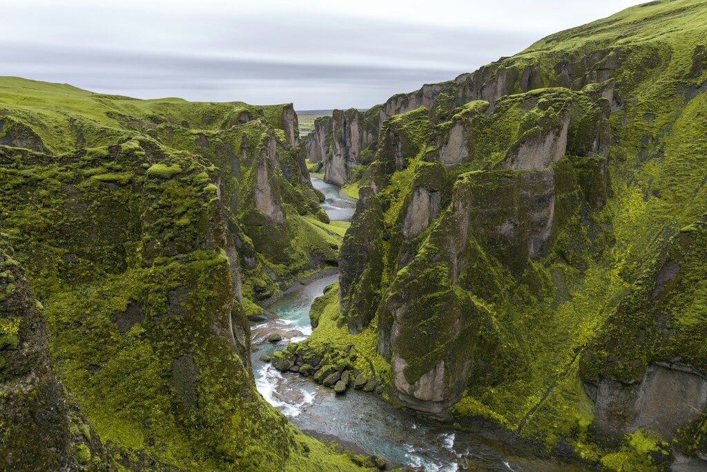 Green moss cliff with river in the middle.