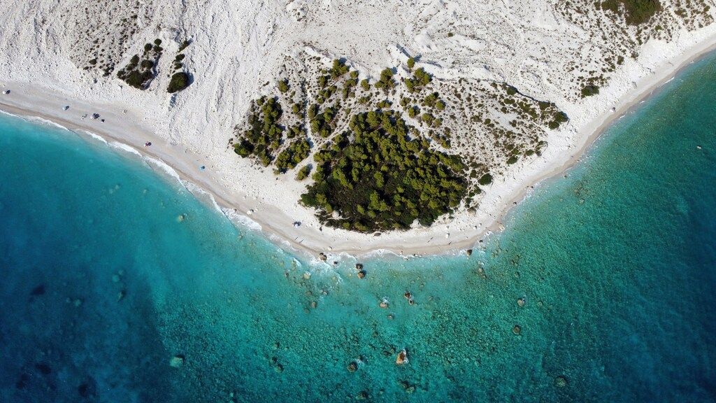 Aerial view of Palasë beach in Albania, with turquoise waters and a patch of greenery.