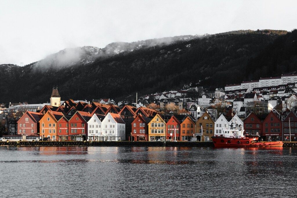 Colorful wooden houses along the waterfront in Bergen, Norway, with misty mountains in the background