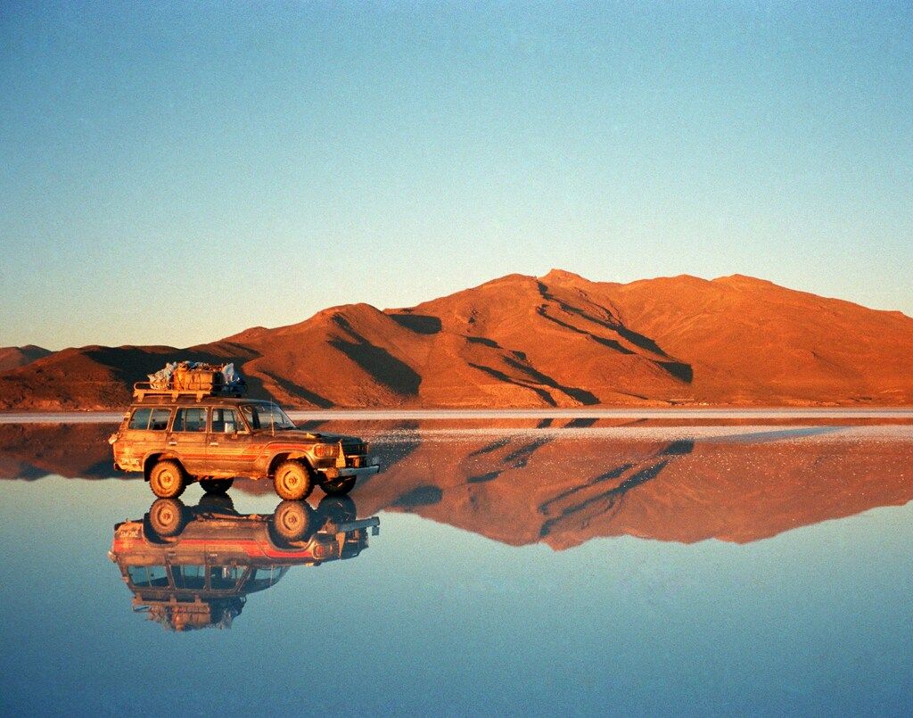A 4x4 vehicle reflecting in the water at Salar de Uyuni, Bolivia