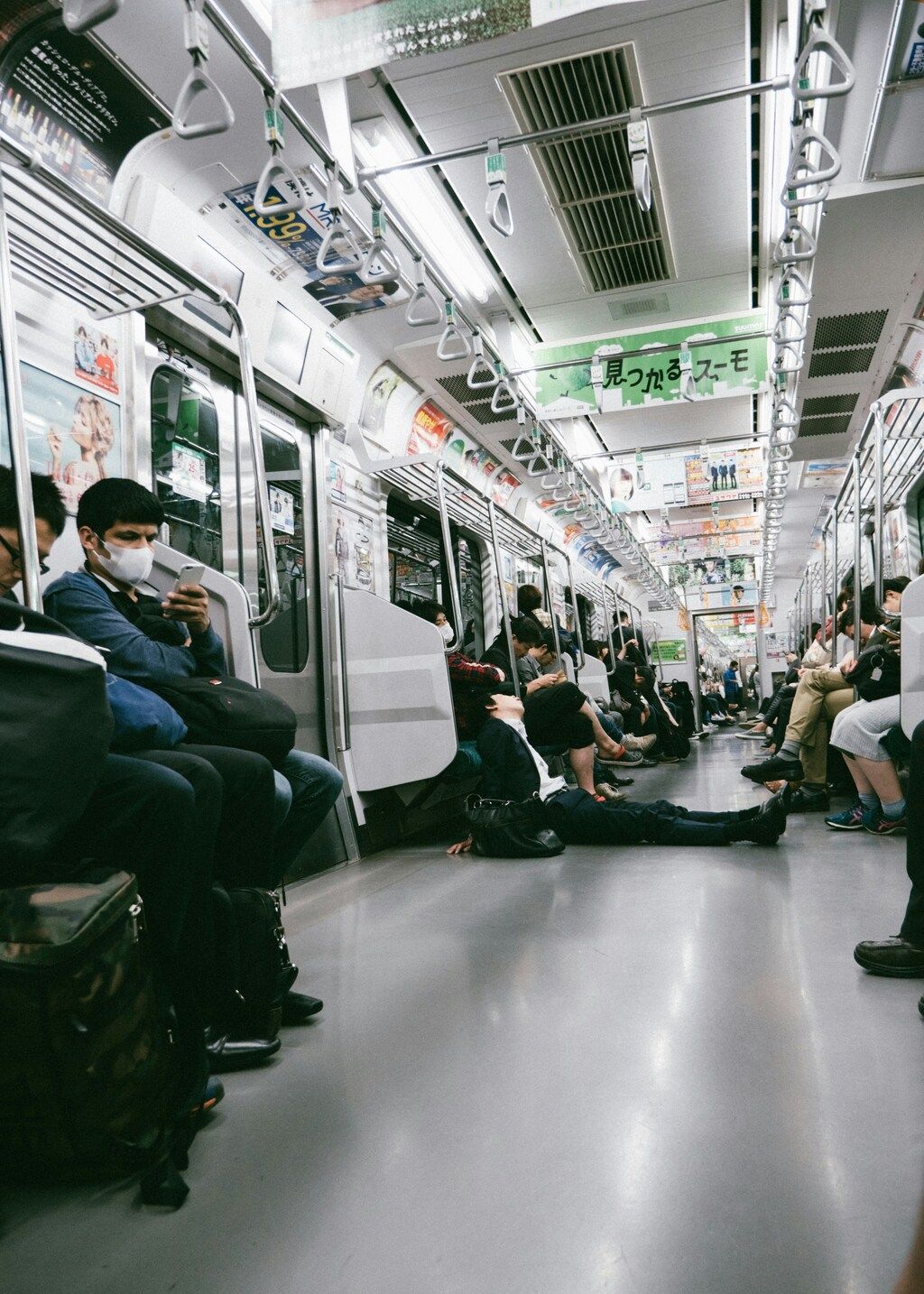 Passengers with face masks sitting and standing inside a crowded Japanese subway train
