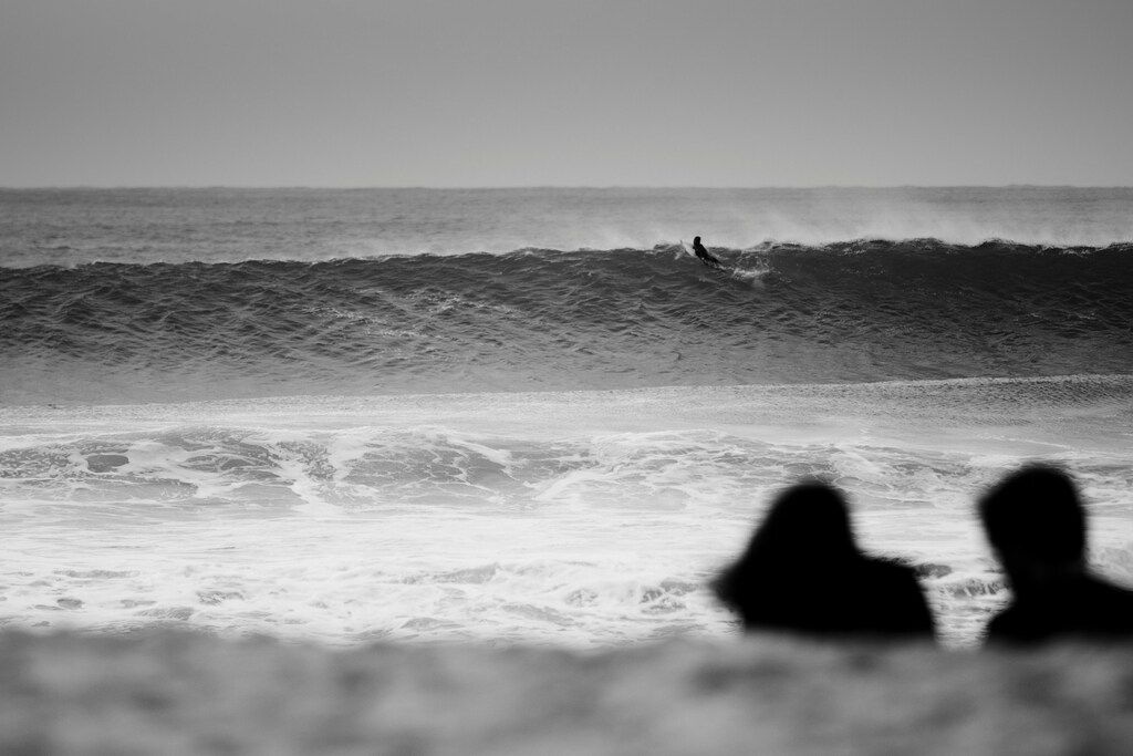 Black and white photo of a surfer riding a large wave in Peniche