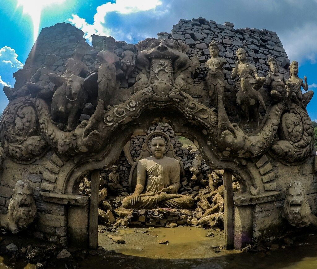 Ancient Buddha statue ruins in Sri Lanka under a bright blue sky