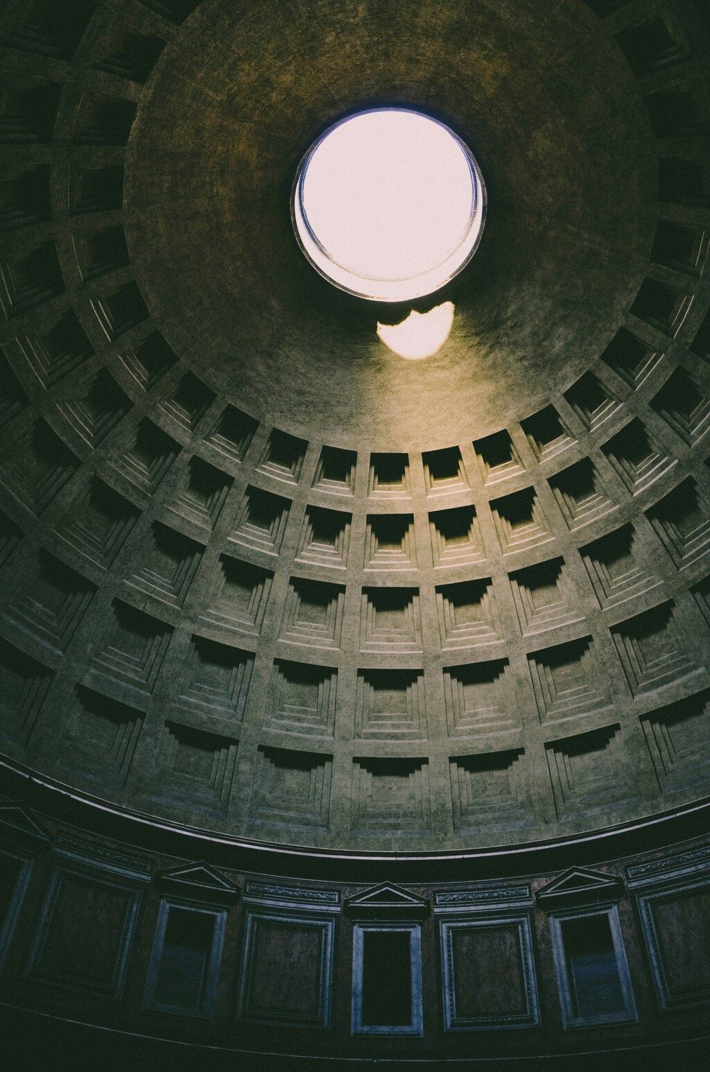 Interior view of the Pantheon in Rome, showcasing the coffered concrete dome with a central oculus that illuminates the cylindrical building.