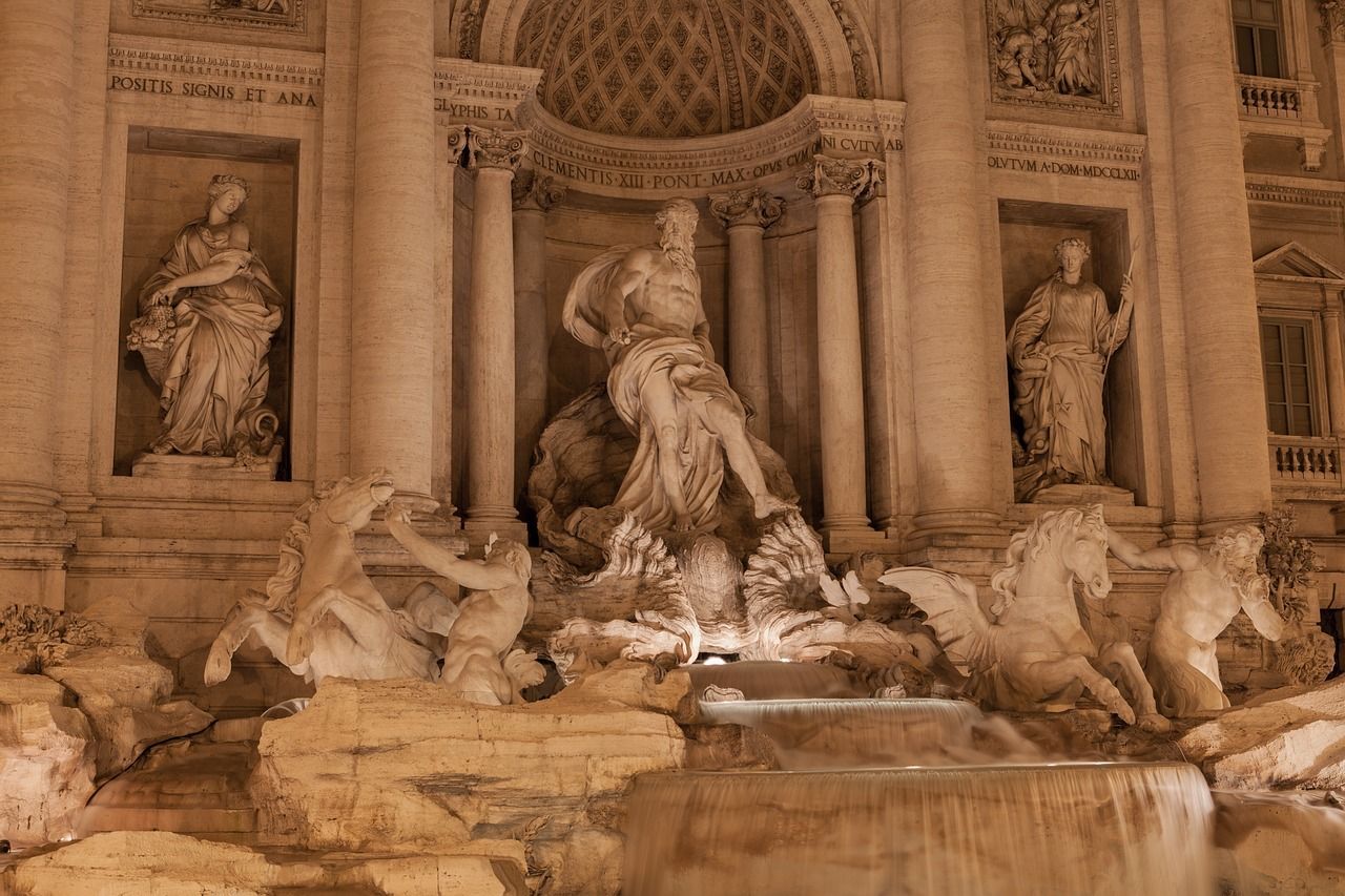 Night view of the Trevi Fountain in Rome, illuminated by lights that highlight the detailed sculptures