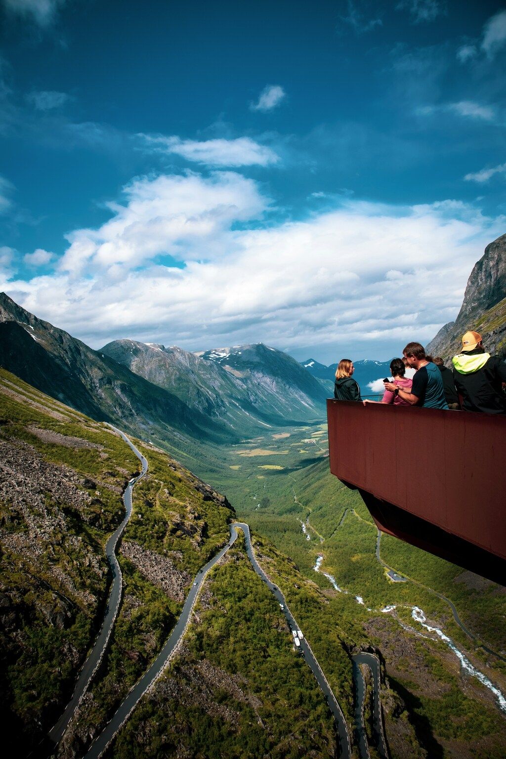 Visitors enjoying the breathtaking view from the Trollstigen viewpoint, overlooking the winding mountain road and lush valley below