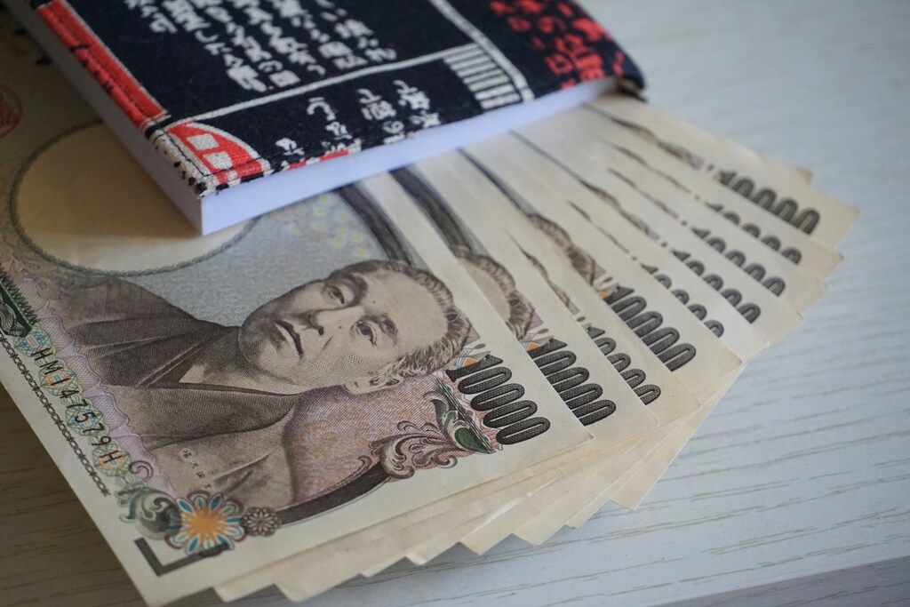 Japanese yen banknotes spread out with a notebook on a table