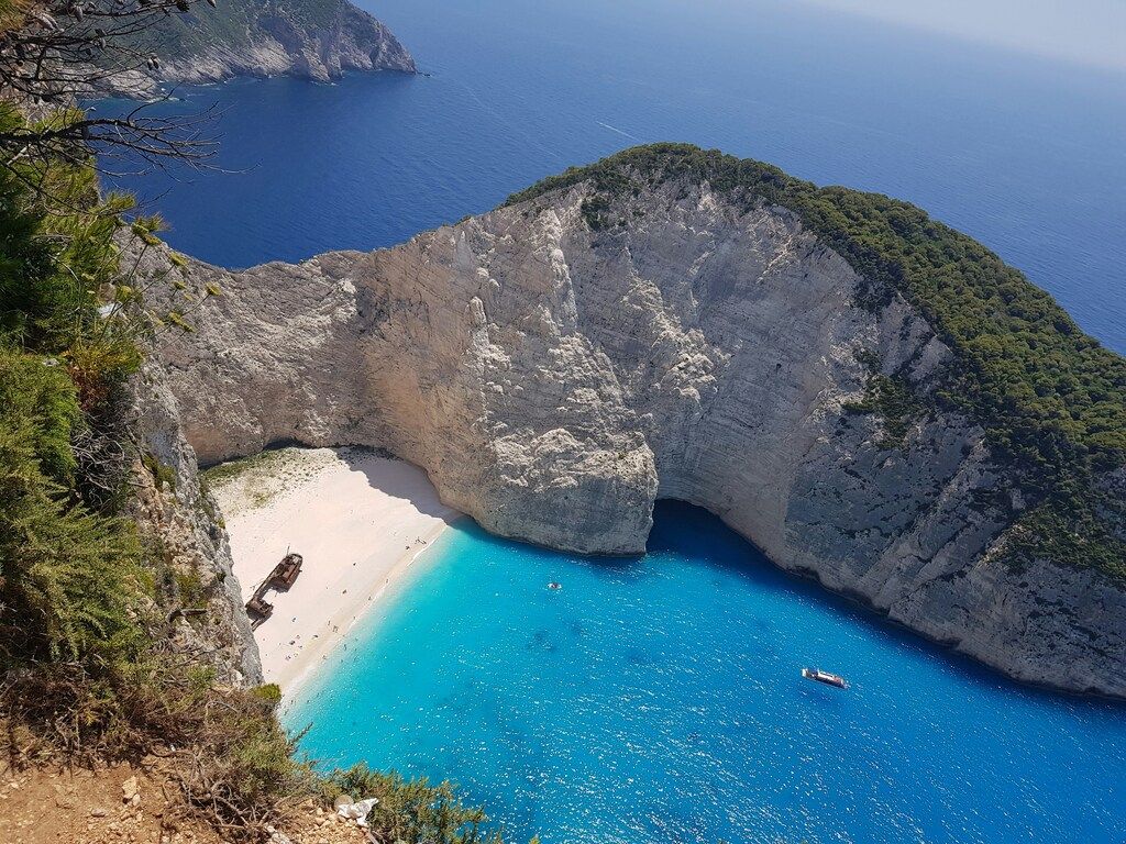 A breathtaking view of Navagio Beach on Zakynthos, featuring a shipwreck on the white sandy shore, surrounded by turquoise waters and steep cliffs