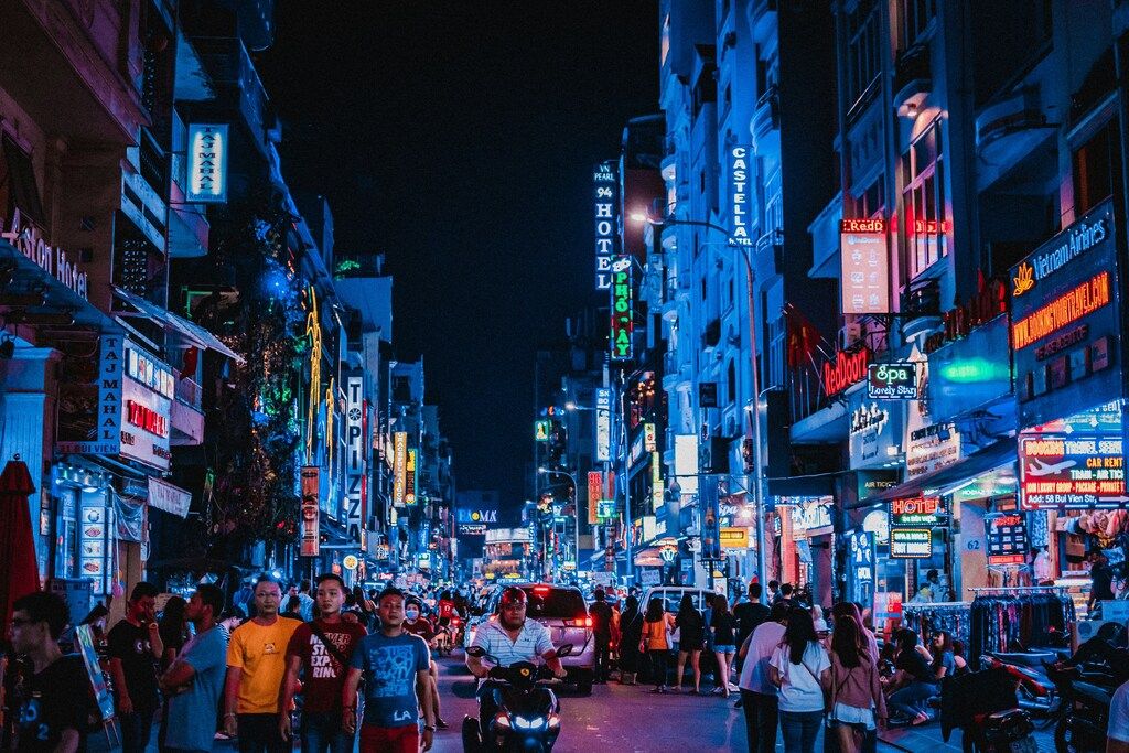 Bustling street scene in Ho Chi Minh City at night, filled with neon signs