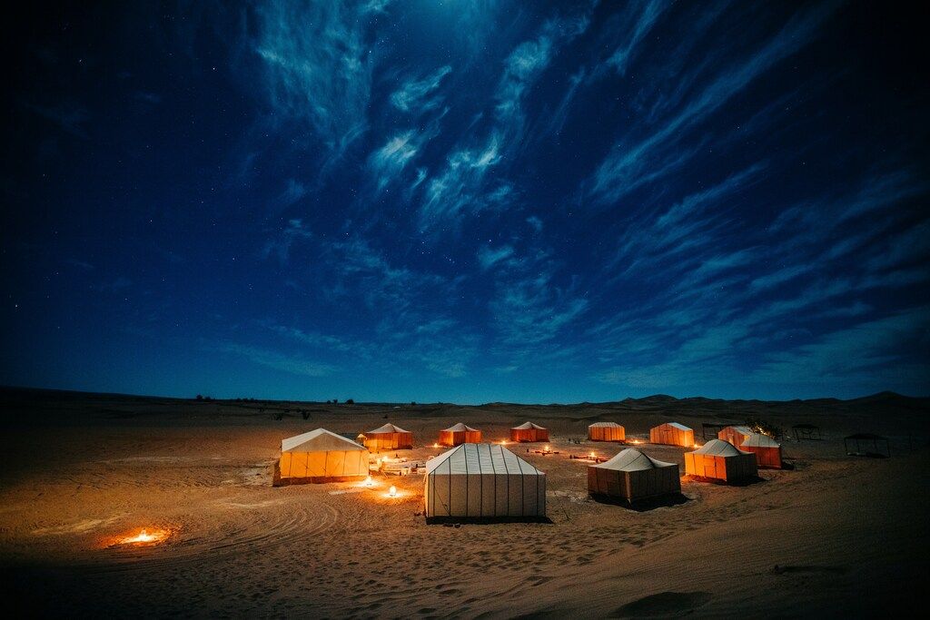 A desert camp with illuminated tents under a starry night sky in Moroco