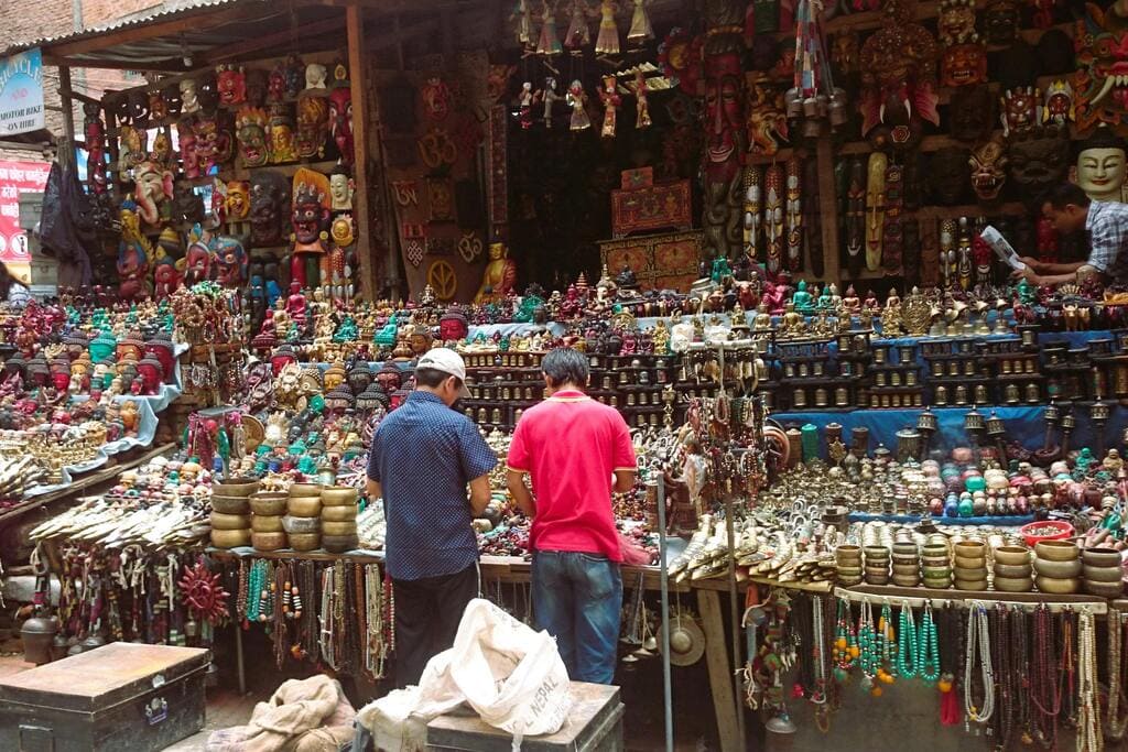 A bustling market in Kathmandu, Nepal, displaying colorful handmade crafts, statues, and jewelry.