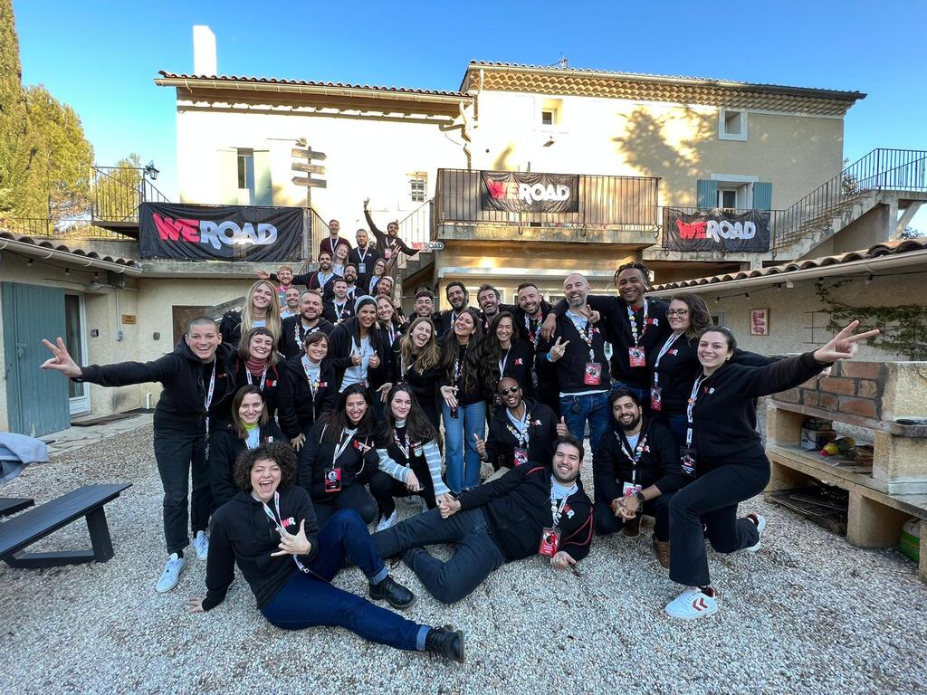 A group of WeRoad travelers enjoying an organized group trip, posing together in front of a charming villa during their Paris adventure.