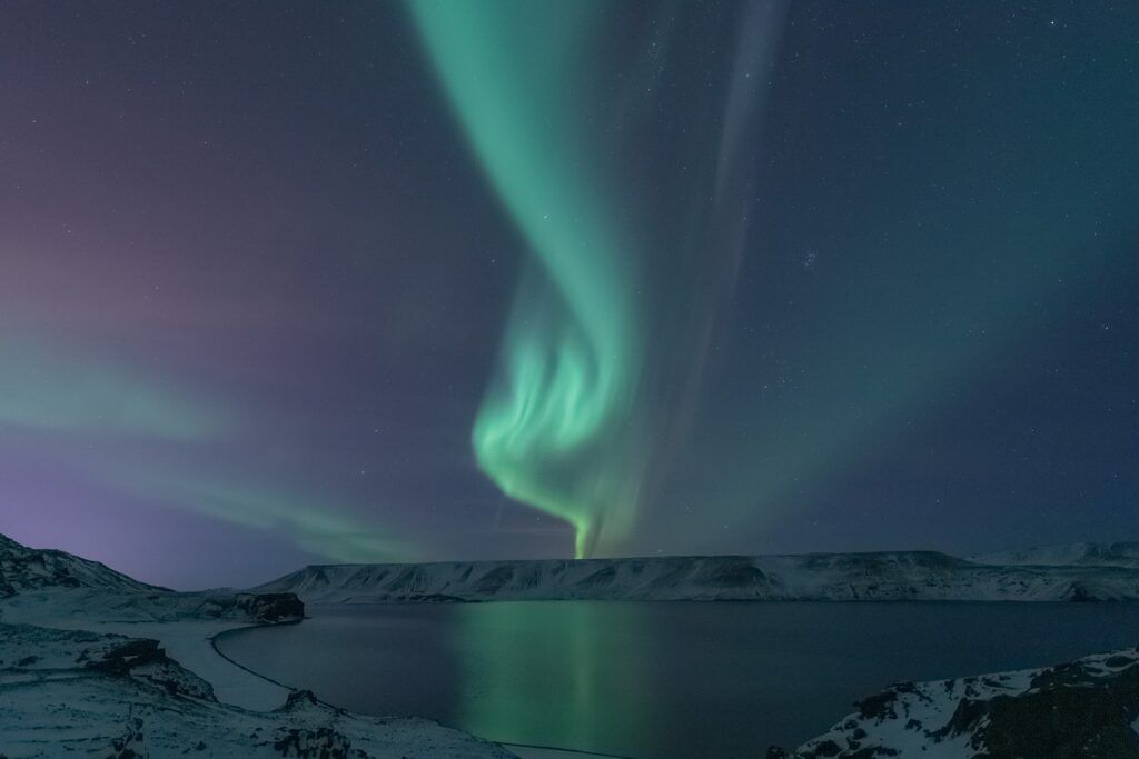 Northern lights illuminating the night sky over a snowy lake in Iceland.