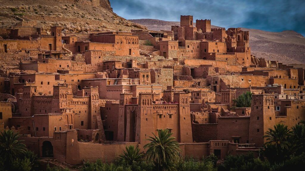 Ancient mud-brick kasbah in Ait Benhaddou, Morocco, under a cloudy sky.