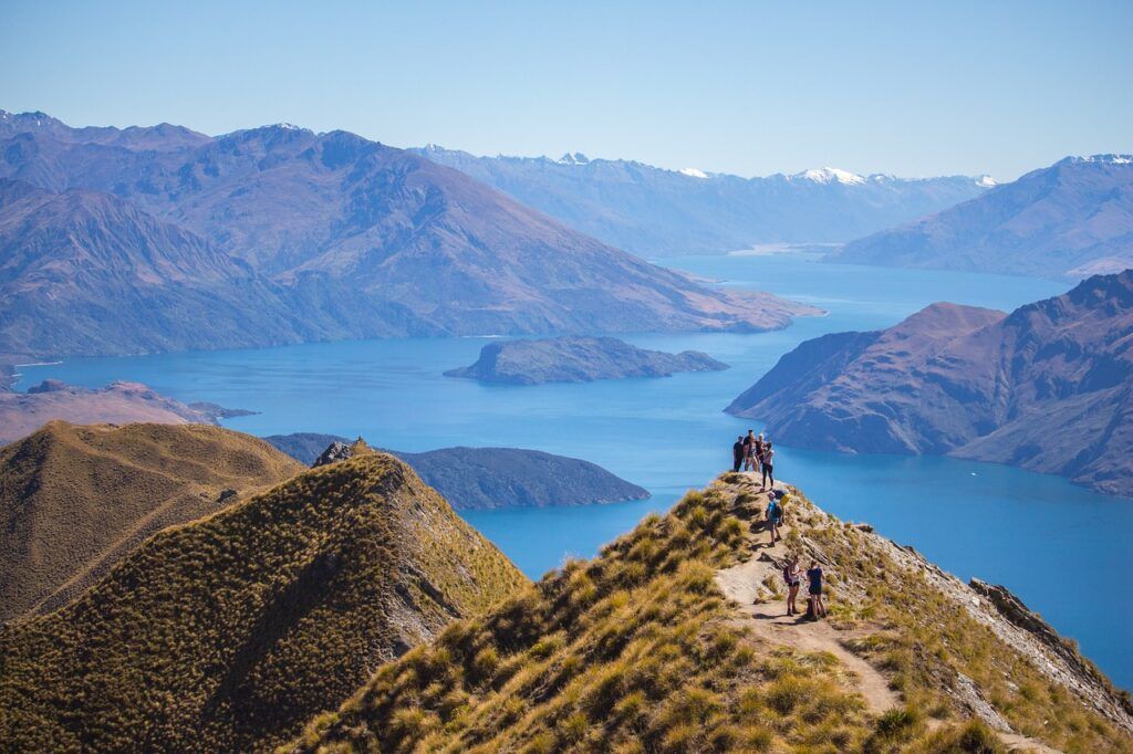 Group of hikers standing atop a scenic ridge overlooking Lake Wanaka in New Zealand.