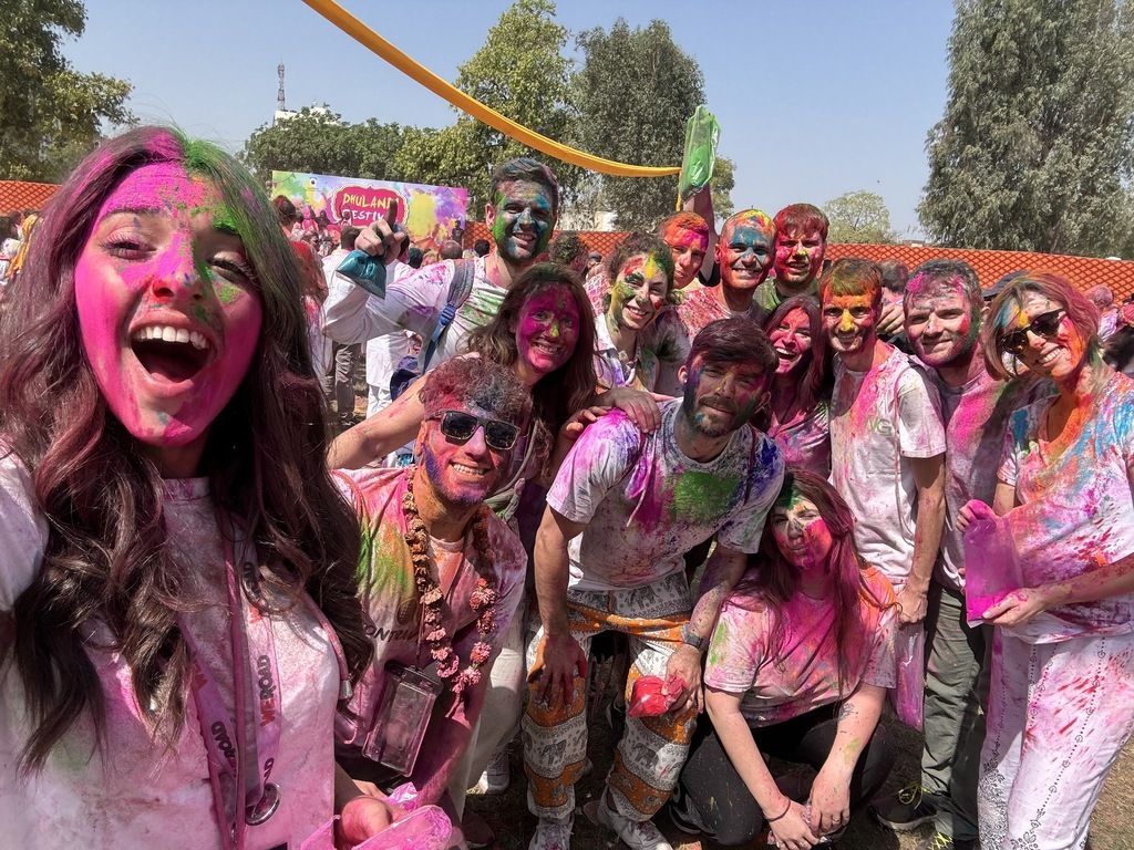 Group of people covered in colorful powders celebrating the Holi festival in India during a WeRoad trip.