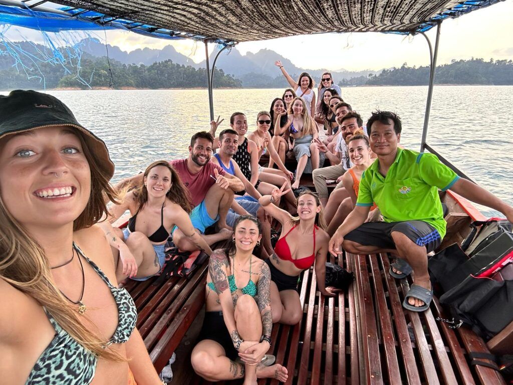 Group of travelers enjoying a boat ride on a lake surrounded by mountains during a WeRoad trip.