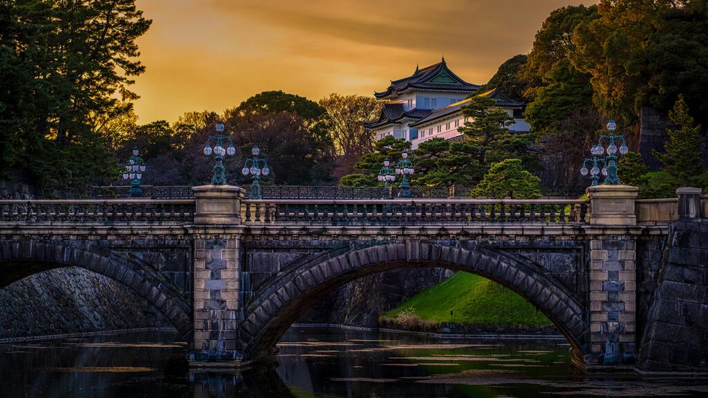 Imperial Palace in Tokyo, Japan, during a beautiful sunset, with a historic bridge in the foreground.