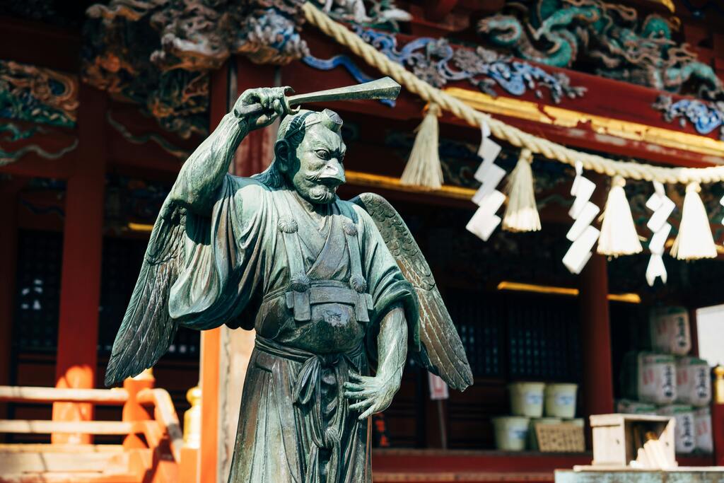 A statue of a tengu deity in a Japanese shrine, representing traditional folklore.