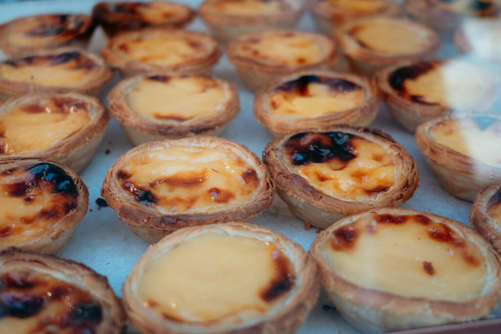 Traditional Portuguese egg custard tarts, known as "pastéis de nata," displayed in a bakery window.