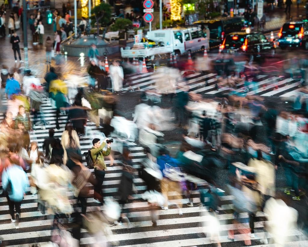 A busy Shibuya Crossing in Tokyo, Japan, with blurred pedestrians creating a dynamic atmosphere.