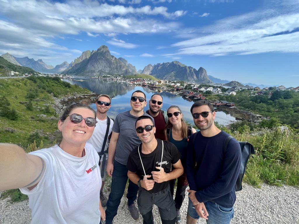 Smiling travelers posing in front of a picturesque Norwegian fjord and mountains during a WeRoad group trip.