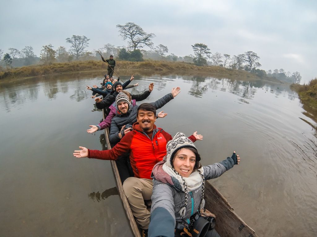 A WeRoad group enjoying a traditional wooden canoe ride through the calm waters of Chitwan National Park, Nepal.