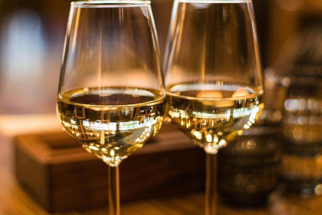 Two glasses of white wine illuminated by soft lights in an elegant setting.