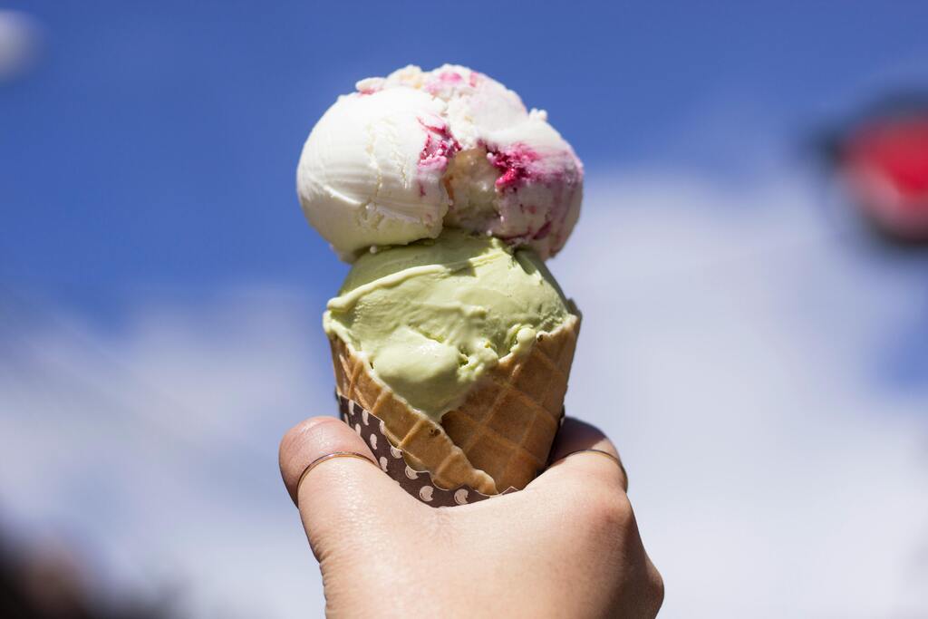 Artisanal ice cream cone with two flavors: pistachio and fiordilatte with berries