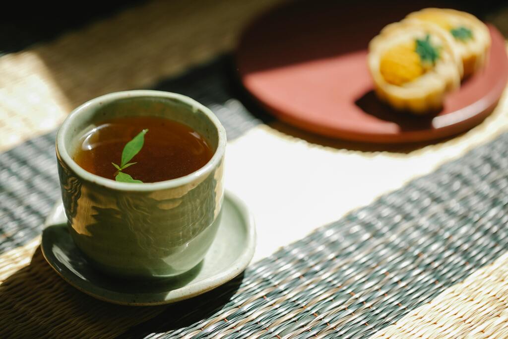 A ceramic cup of traditional Moroccan mint tea served on a woven mat, with pastries in the background.