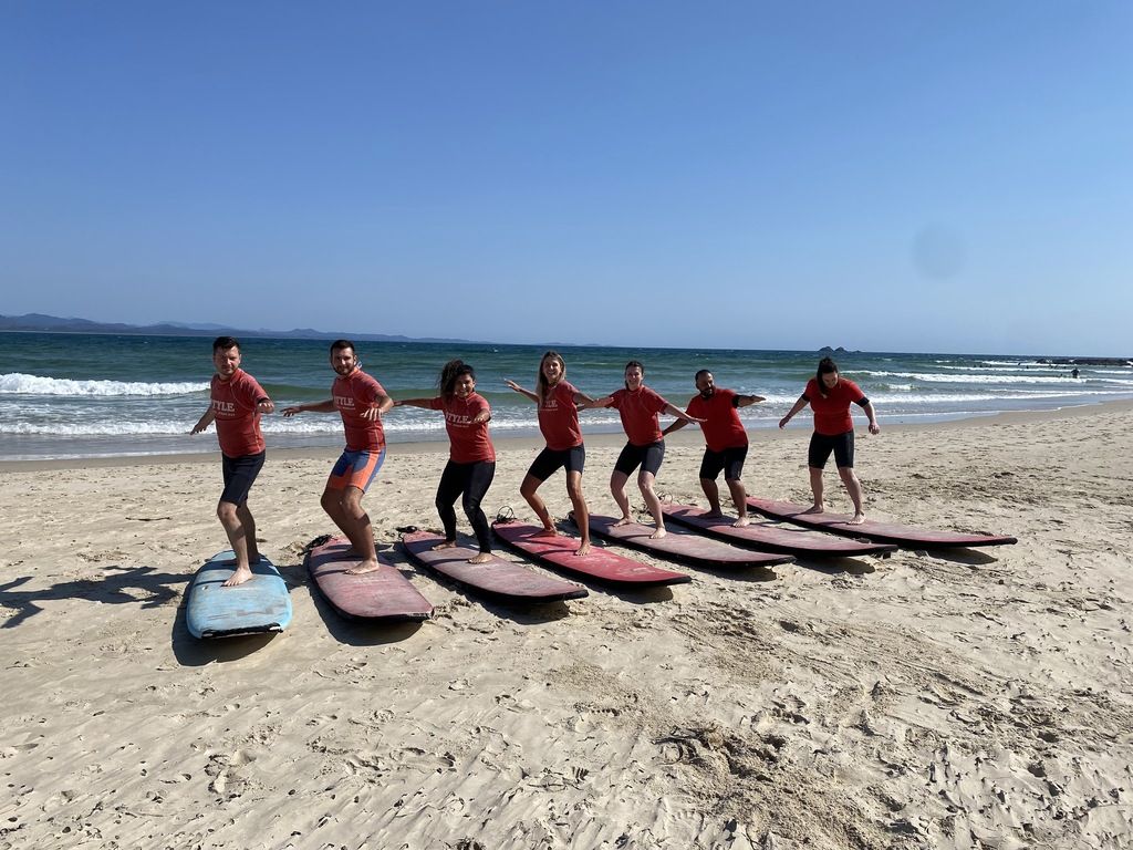 Group surfing lesson on an Australian beach with a clear blue sky.