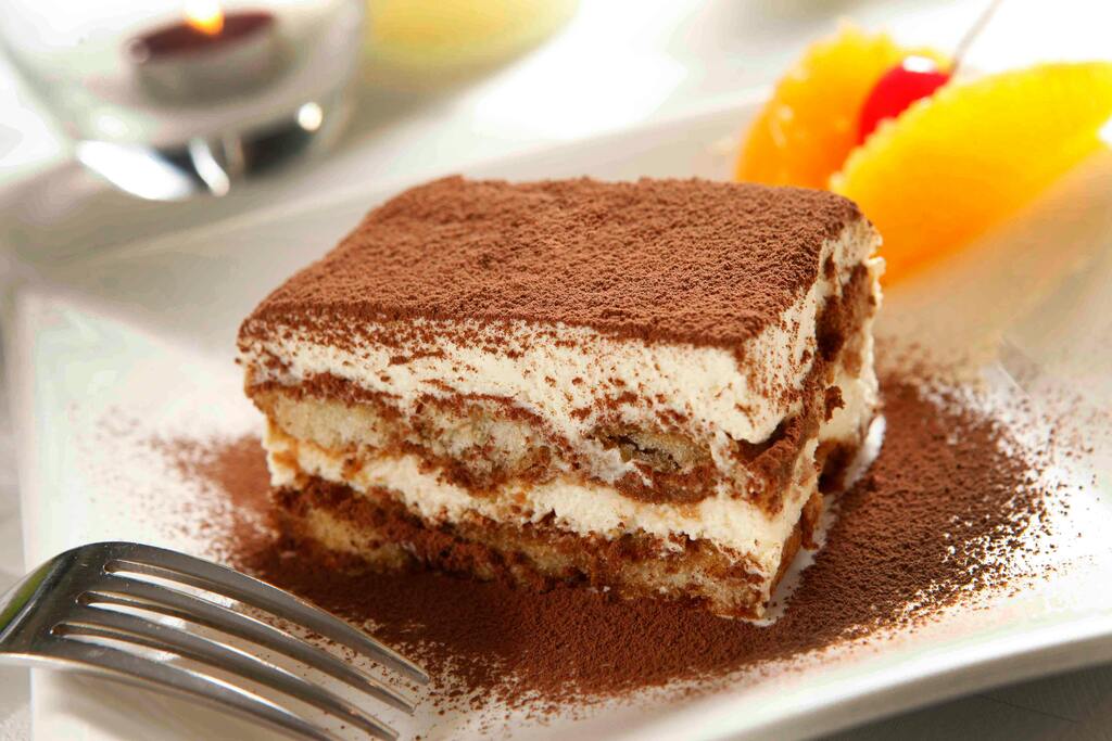 Tiramisu served on a plate with cocoa powder and fruit decorations