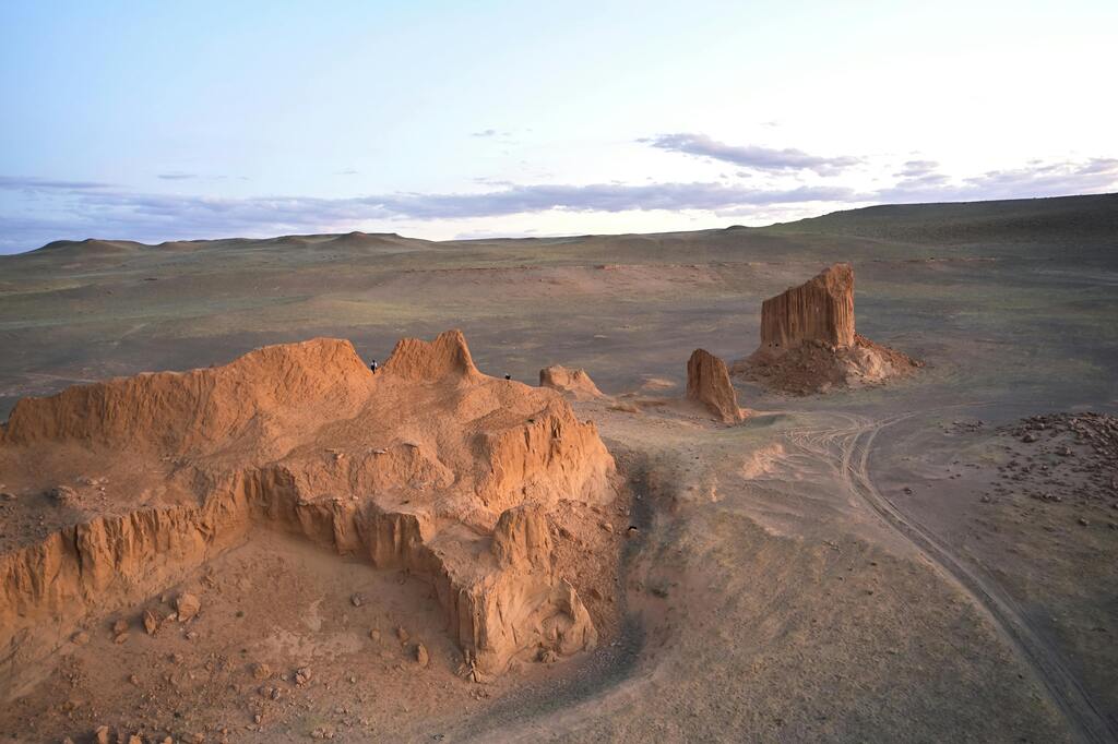 The dramatic landscape of the Flaming Cliffs in the Gobi Desert, bathed in soft sunset light.