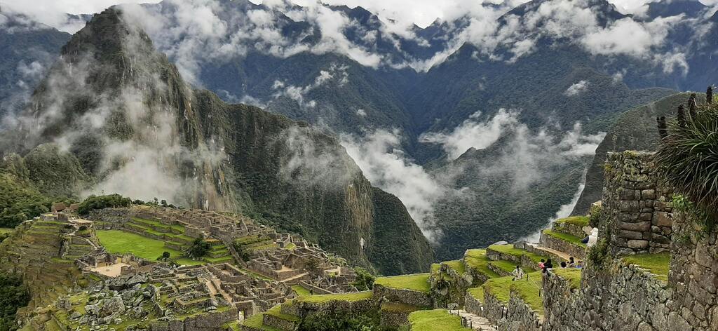 A breathtaking view of the ancient Inca ruins of Machu Picchu, nestled among the green Andean mountains with mist rolling in.