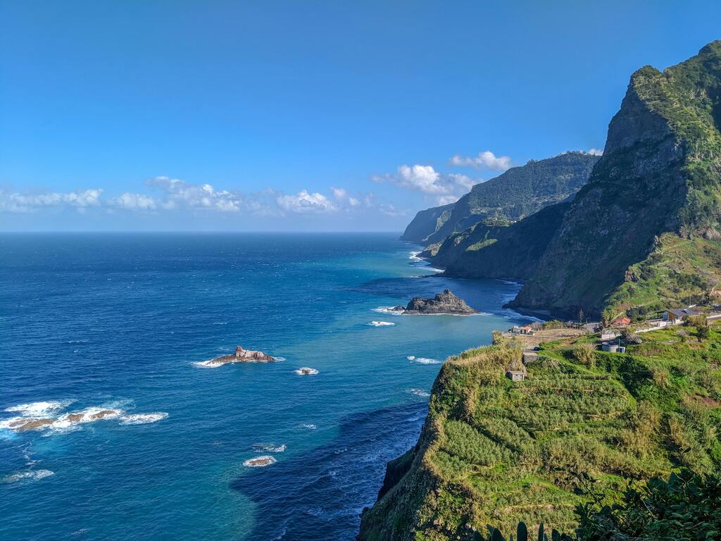  A stunning view of the green cliffs and blue Atlantic Ocean along the rugged coastline of Madeira, Portugal.