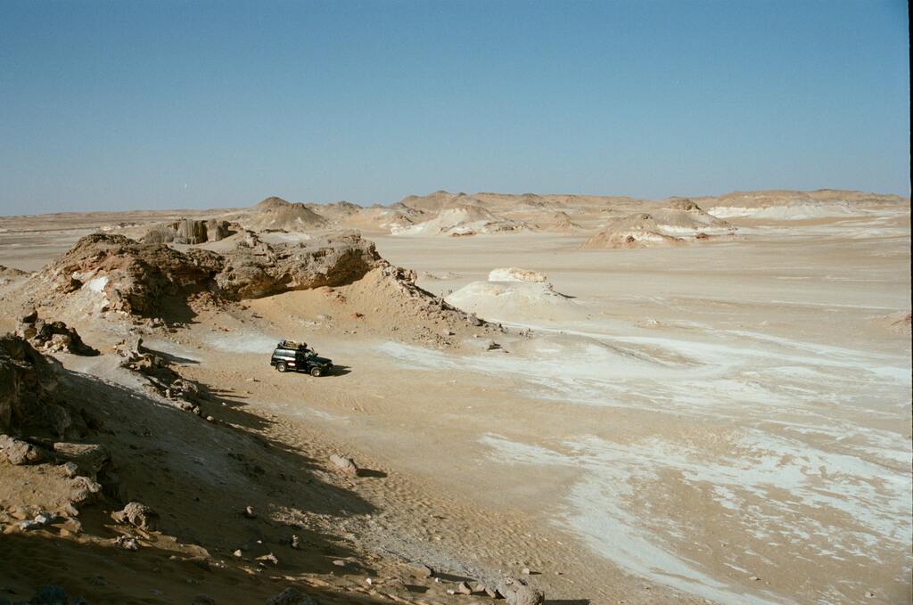4x4 vehicle exploring the White Desert in Egypt, surrounded by rocky outcrops and sand.