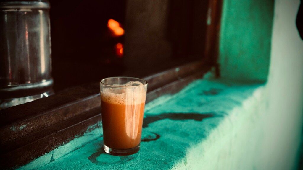 Glass of wood apple juice placed on a turquoise windowsill with a warm glow in the background