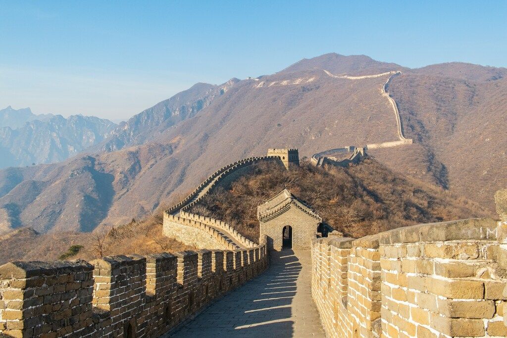 Panoramic view of the Great Wall of China stretching over the mountains on a clear day.