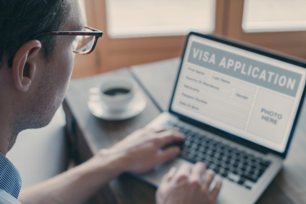 A person filling out an online Visa Application form on a laptop.