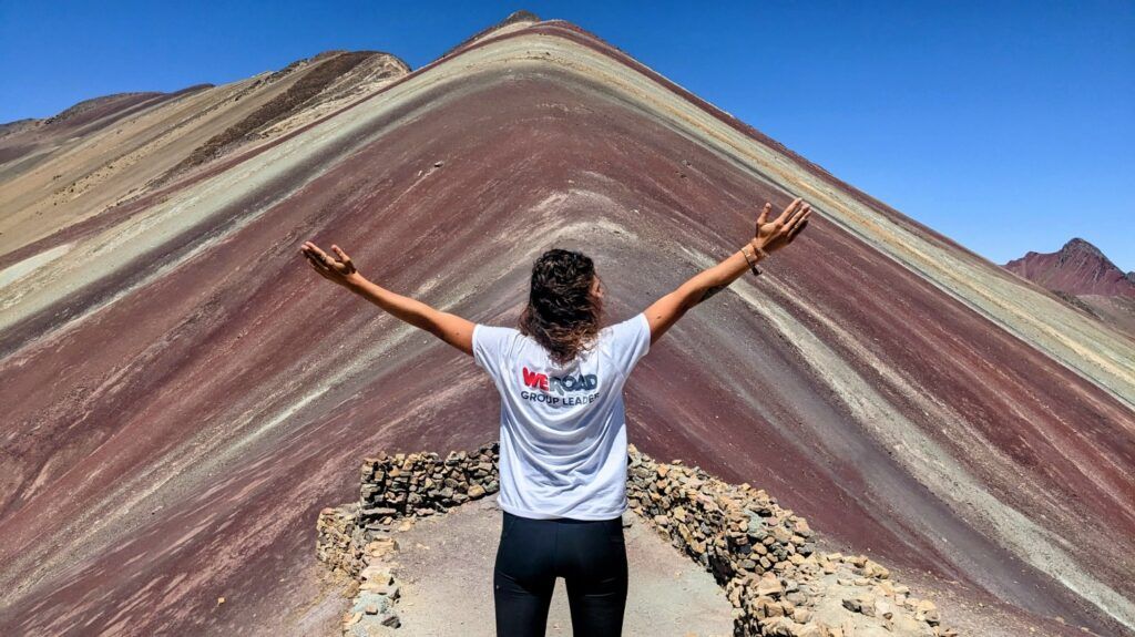 WeRoad Group Leader raising arms on Vinicunca peak at Rainbow Mountain, Peru.